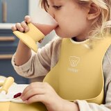 BABYBJORN komplet jedilni set slinček, krožnik, lonček, žlica in vilice Powder Yellow | Shoptok.si